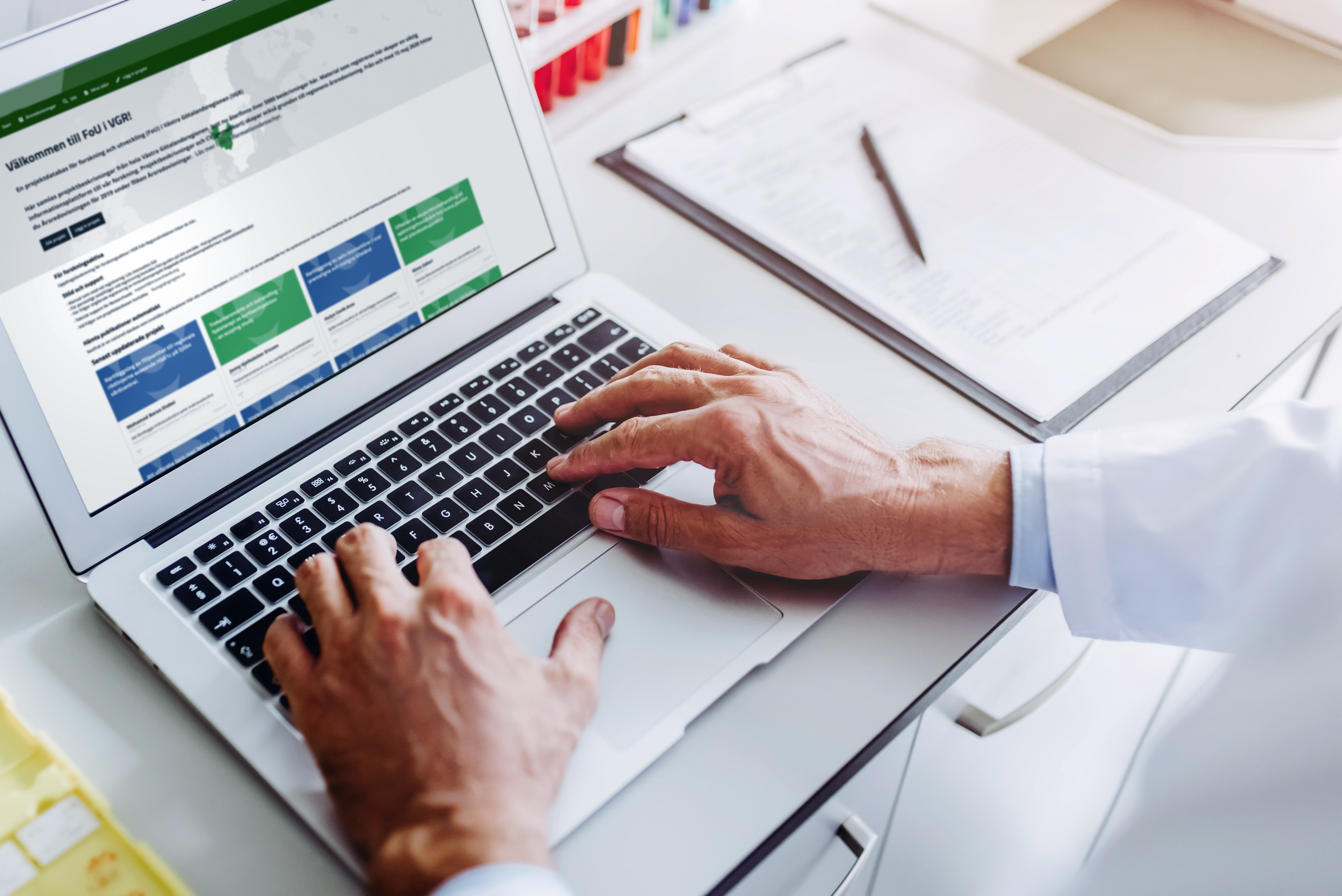 Foto på en bärbardator med en bild av Projektdatabasen FoU i VGR på skärmen