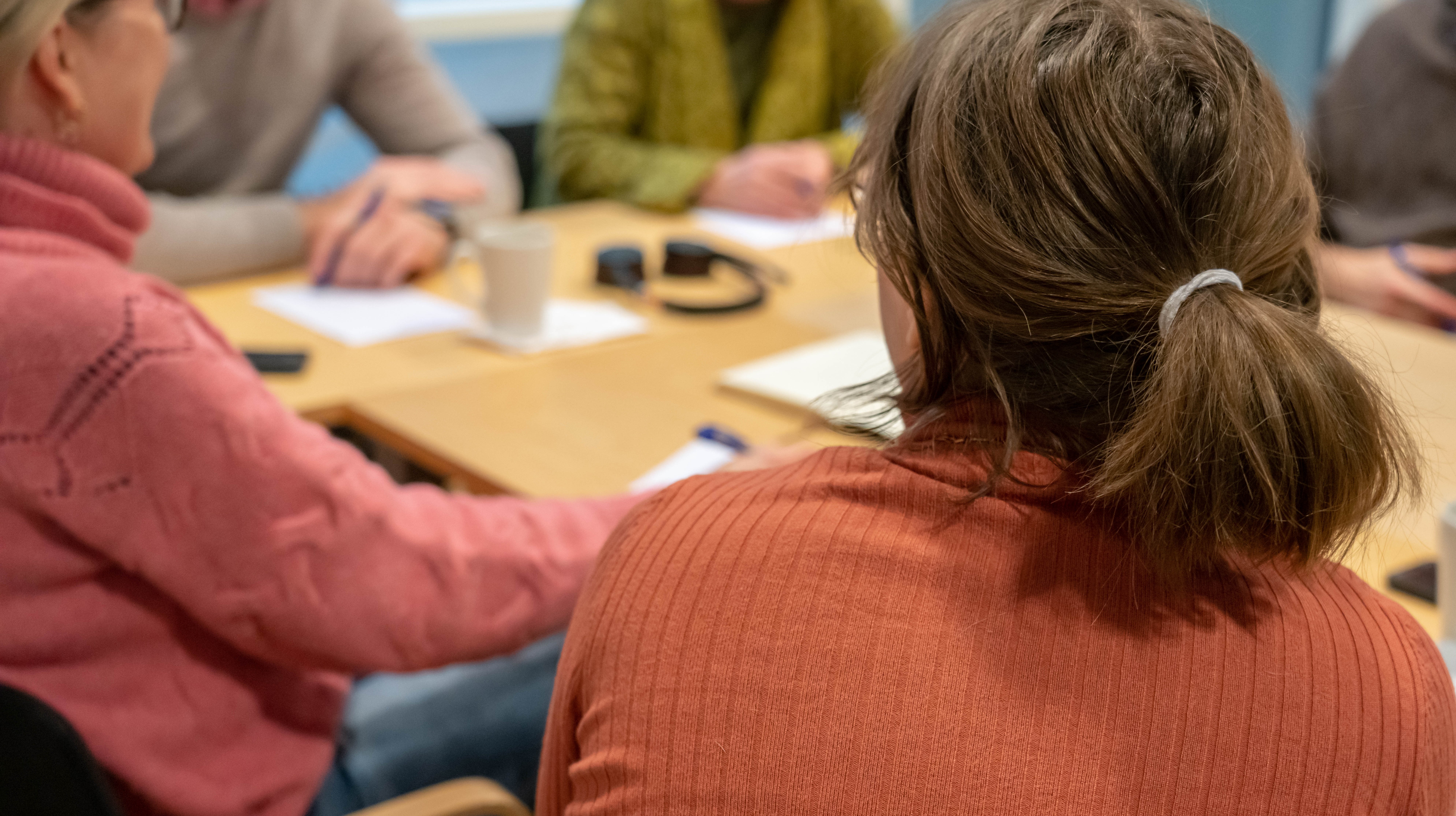 Människor sitter runt ett bord och diskuterar 