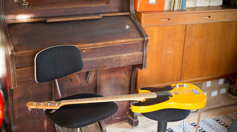 En tramporgel och en gul elbas som ligger på en stol. I bakgrunden syns en bokhylla.