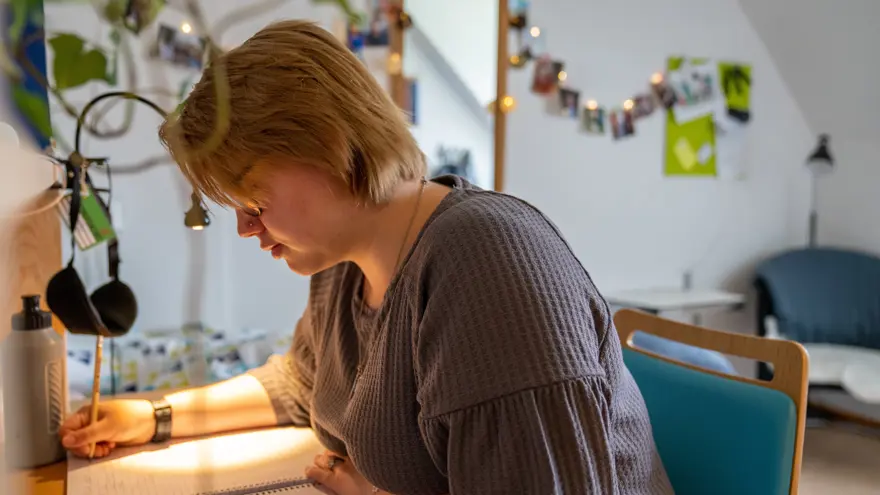 Interiörbild där elev sitter vid skrivbordet i sitt rum