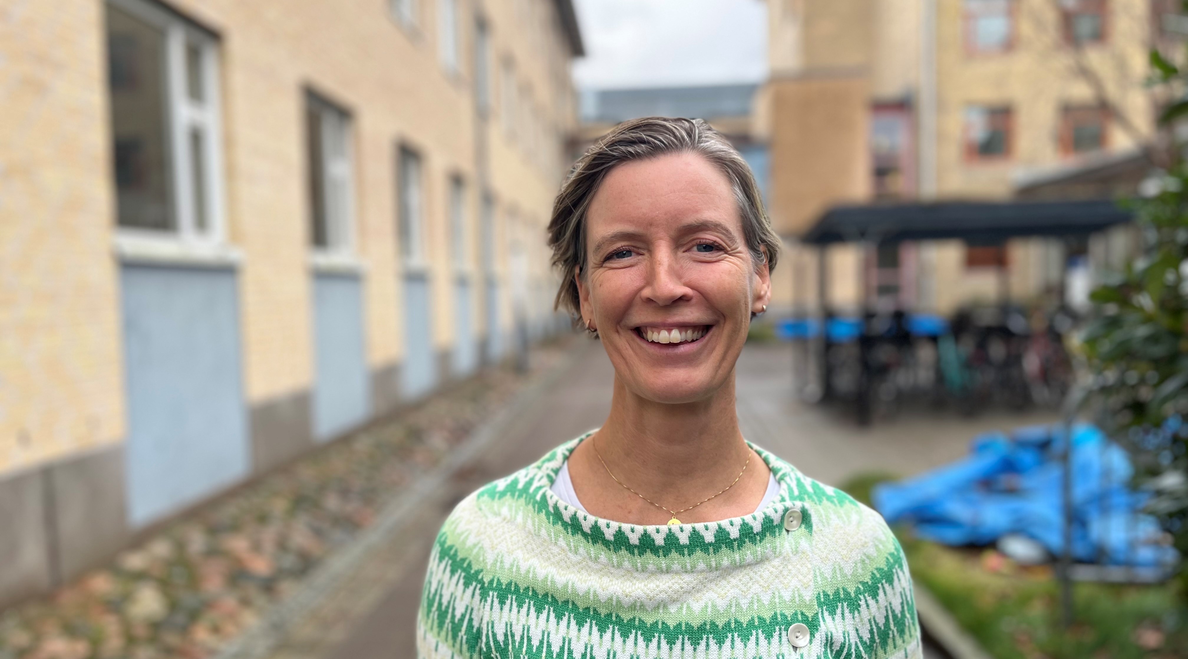 Katarina Nyström står utomhus i ett blåsigt Göteborg i november. Hon ler med hela ansiktet och ser väldigt glad ut.