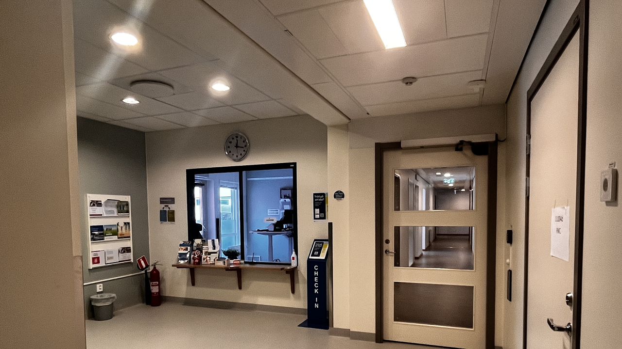 Reception med glasfönster, anslagstavla till vänster och klocka ovanför.