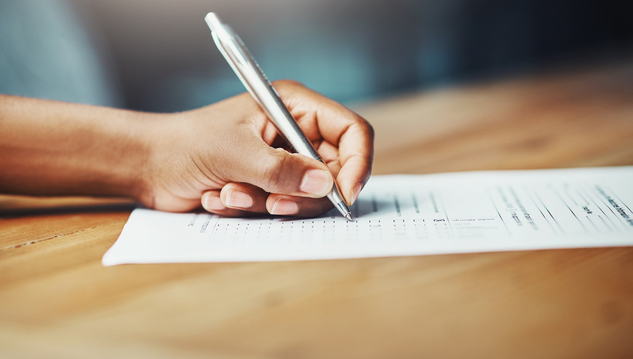 En hand som fyller i ett formulär med penna