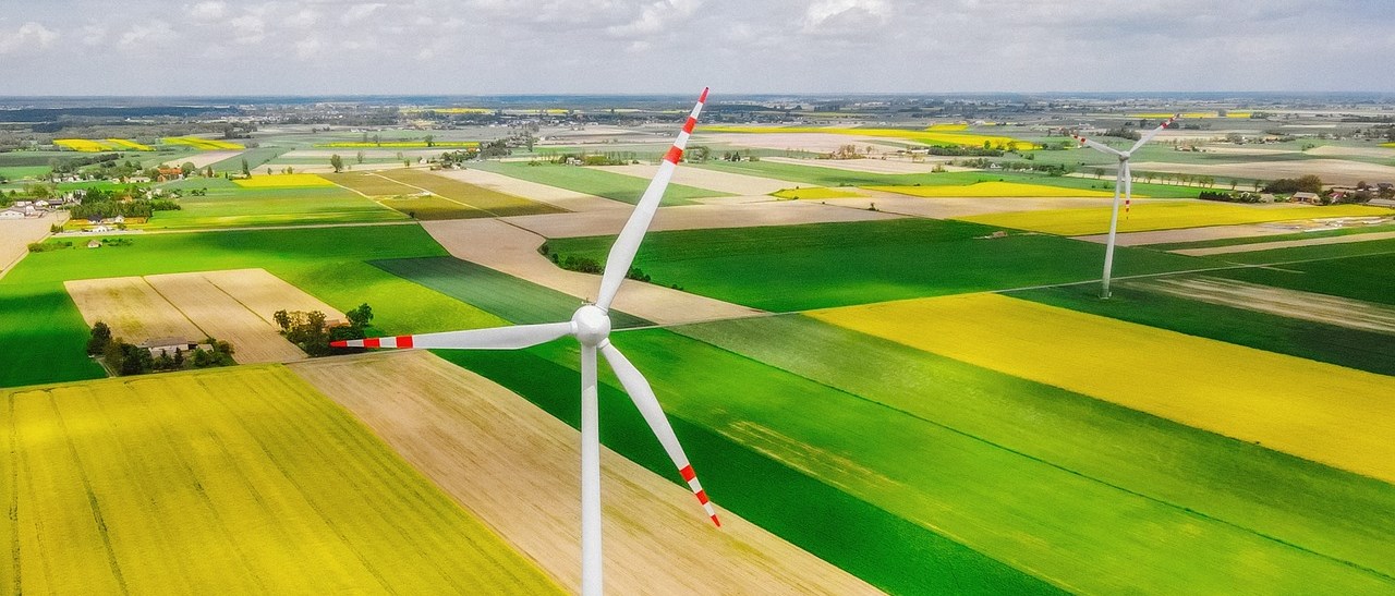 Öppet landskap med odlingsfält och vindkraftverk