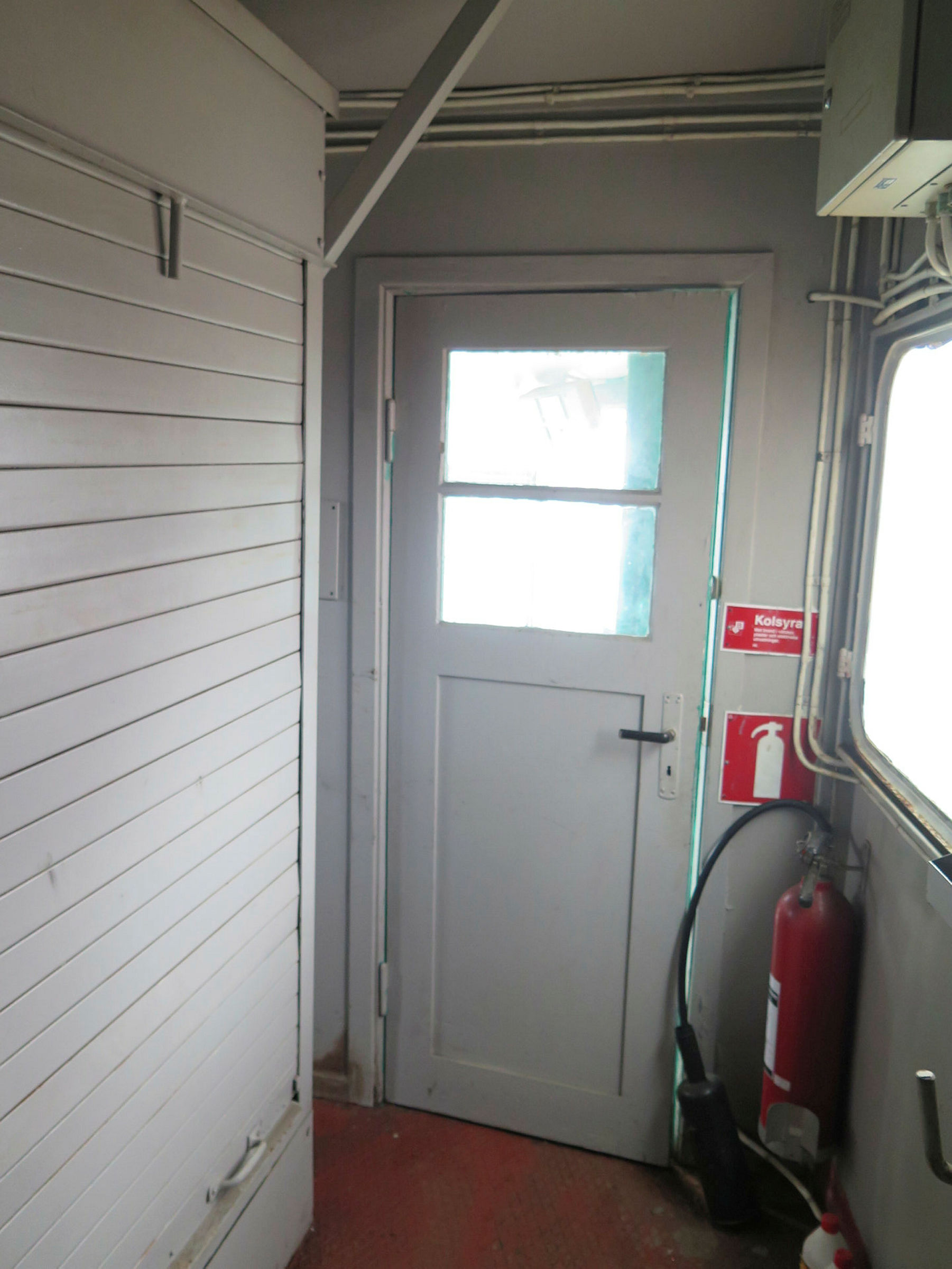 Inifrån kran 43, dörr som leder ut och brandsläckare, vita väggar