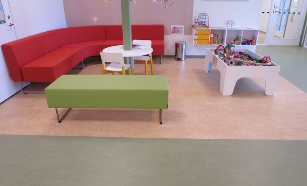 Väntrum med en röd soffa och leksaker