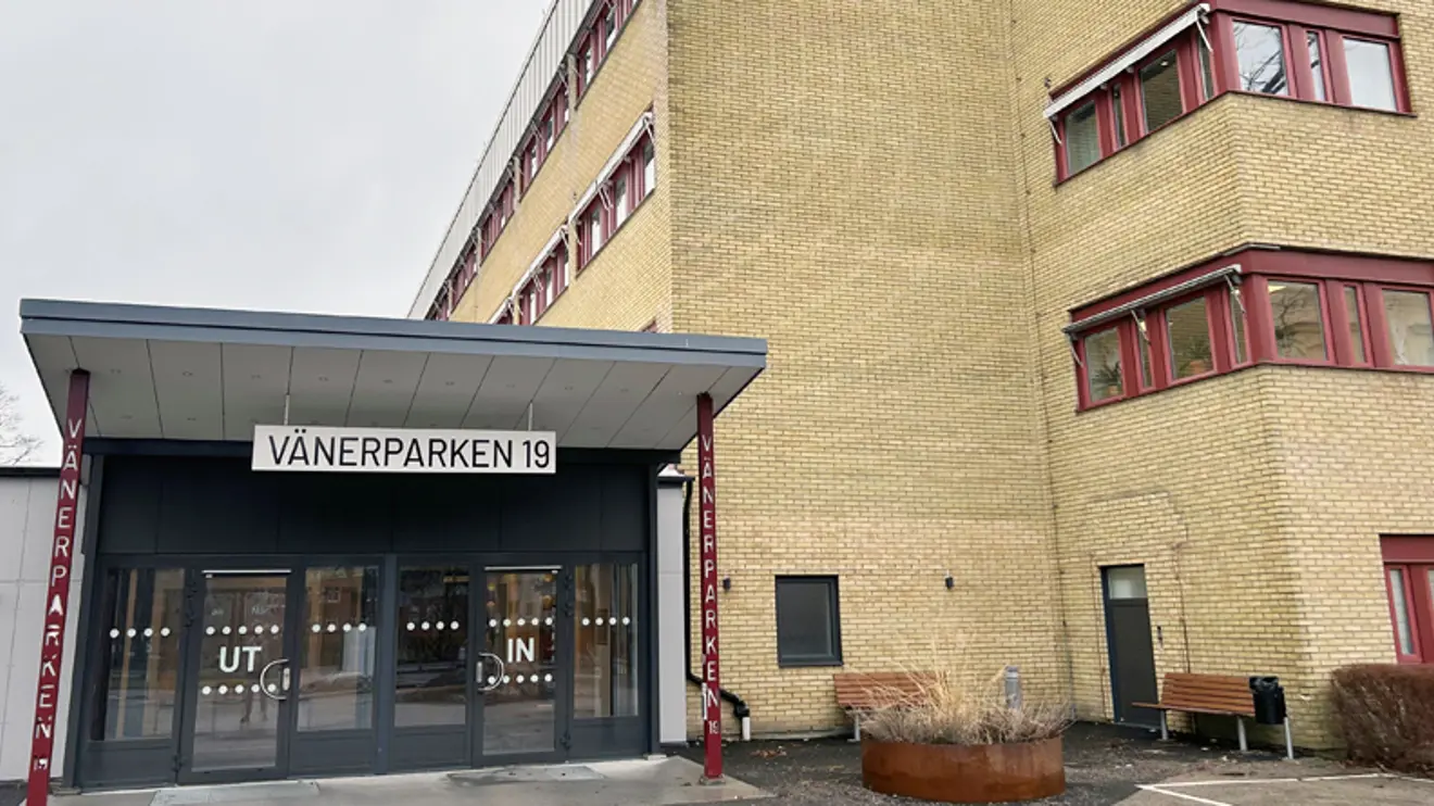 Entré med glaspartier brevid gul tegelbyggnad